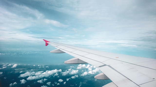 an airplane wing with the blue sky surrounding it