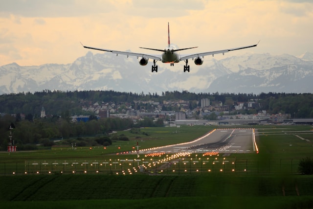 a plane landing on a runway with snowy mountains in the distance