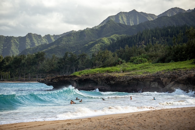 a beach with big waves and a giant mountain in the background