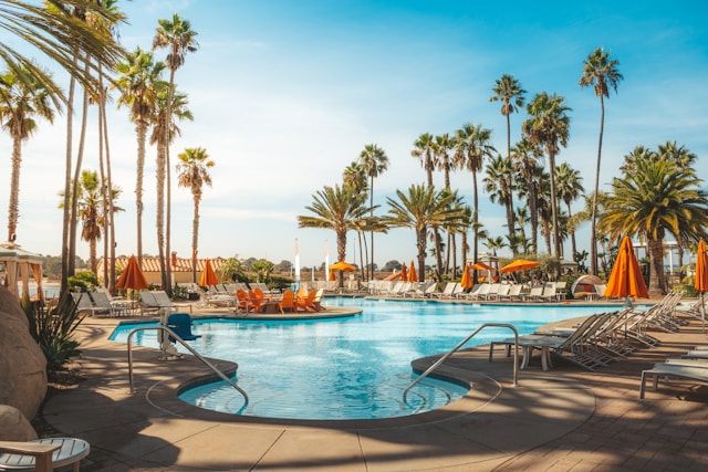 a pool surrounded by beach chairs and palm trees